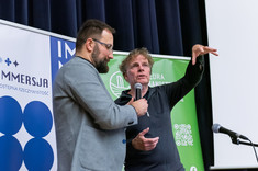 Dwóch mężczyzn prowadzi wykład. Starszy mężczyzna ubrany na czarno tłumaczy coś zebranym, drugi w jasnej marynarce stoi obok. Od prawej: prof. arch. W. Maas, dr. arch. A. Truszczyński.