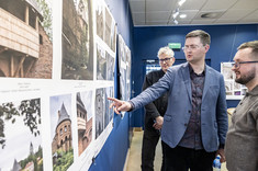 Damian Pękalski wskazuje z zainteresowaniem na jedną z prezentowanych fotografii, obok niego stoją Aleksander Busz i Przemysław Gąsiorski