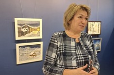 Pani Profesor Galina Kalda opowiada o swoich obrazach. Stoi na tle niebieskiej ściany, fot. dr inż. arch. Joanna Dudek