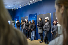 Zaproszeni goście stoją na tle niebieskiej ściany i oczekują na ogłoszenie wyników konkursu