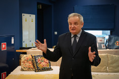 Pan Dziekan Lech Lichołai wita przybyłych gości na tle haftowanych obrusów i poduszek