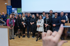 Zdjęcie grupowe kilkunastu osób, mężczyzn i kobiet. Większość ubrana na czarno. Wszyscy się uśmiechają. W tle scena sali wykładowej. Od lewej: dr. arch. B. Walicka-Góral, dr. arch. K. Kozłowska, dr. M. Zub, arch. A. Jóźwiakowska, arch. D. Bober, prof. arch. W. Maas, prof. arch. A. Sikora, arch. A. Pomykała, arch. N. Ludwikowska, arch. M. Bober, dr arch. J. Dudek, dr. arch. A. Truszczyński, arch. J. Dudek, arch. Ł. Bajda.