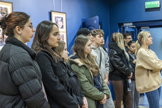 Uczestnicy finisażu wystawy pt. "Ludzie i przestrzeń" na tle niebieskiej ściany, na której wiszą fotografie, fot. Beata Motyka 