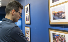 Mężczyzna ogląda fotografie wiszące na niebieskiej ścianie