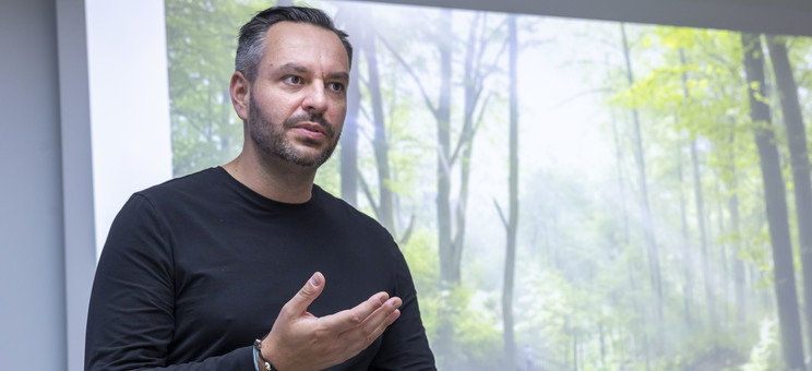 Prelegent Maciej Franta opowida o swoim projekcie. Na tle jego postaci znajduje się zdjęcie prezentacji.