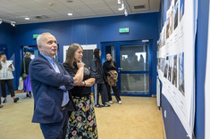 Dwóch mężczyzn z ciemnymi włosami i brodami przygląda się wystawie. Jeden z nich wskazuje jedno ze zdjęć ręką. Na zdjęciu od prawej: arc. Ł Bajda, arch. J. Dudek.