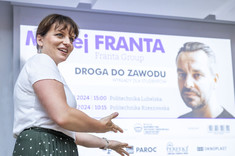 Joanna Dudek wita uczestników wykładu. W tle jej postacji znajduje się slajd prezentacji.