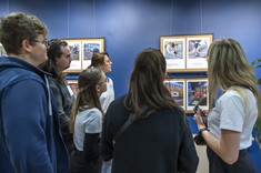 Grupa kilku uczestników finisażu wystawy pt. "Ludzie i przestrzeń" przygląda się wiszącym na ścianie fotografiom, fot. Beata Motyka 