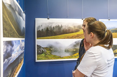 Dwie kobiety przyglądają się planszom z fotografiami pejzaży górskich.