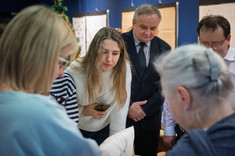 Zgromadzeni goście wystawy słuchają Pani Agaty opowiadającej o swoich haftach