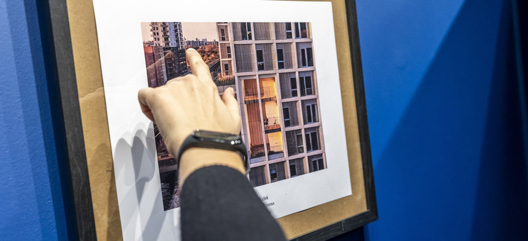 Dłoń wskazuje fragment budynku na fotografi przedstawiającej widok na miasto, fot. Beata Motyka