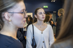 Zdjęcie grupy osób na tle wystawy. Na pierwszym planie dwie młode kobiety. Na zdjęciu na pierwszym palnie: studentki kierunku architektura.