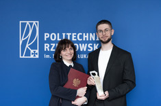 Od lewej: dr inż. arch. Joanna Dudek oraz mgr inż. arch. Przemysław Dybaś pozują do zdjęcia na tle niebieskiej ściany, fot. Arkadiusz Surowiec