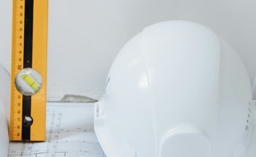 Kask budowlany, plan i poziomica symbolizują trwający remont