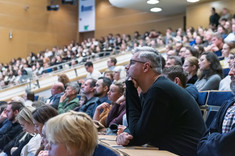 Zbliżenie na słuchaczy wykładu siedzących w rzędach.
