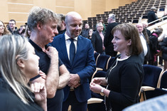 Na pierwszym planie grupa czterech osób podczas swobodnej rozmowy, dwie kobiety i mężczyzna ubrani na czarno i mężczyzna w ciemnym garniturze. Od lewej: prof. arch. A. Sikora, prof. arch. W. Maas, prez. K. Fijołek, dr. arch. J. Dudek.