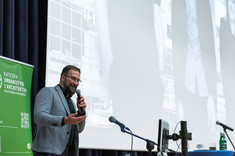 Mężczyzna w jasnej marynarce przemawia do zebranych. W tle jasny ekran prezentacji i w narożniku zielony baner. Dr. arch. A. Truszczyński, TKHolding.