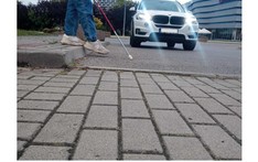 Osoba z laską dla niewidomch przechodzi przez jezdnię