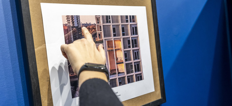 Dłoń wskazuje fragment budynku na fotografi przedstawiającej widok na miasto, fot. Beata Motyka