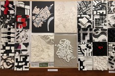 Zbliżenie na ścianę z modelami miast. Większość w biało-czarnej kolorystyce z kilkoma czerwonymi elementami. Pośrodku większe szaro-białe modele.