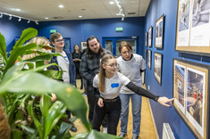Grupa studentów/przedstawicieli koła naukowego „Immersja. Dostępna Rzeczywistość” przygląda się fotografiom wiszącym na ścianie, fot. Beata Motyka