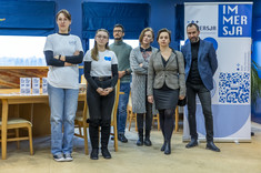 Dwie przedstawicielki koła naukowego „Immersja. Dostępna Rzeczywistość” oraz od lewej: mgr inż. arch. Jakub Dudek, mgr inż. arch. Karolina Kozłowska, dr inż. arch. Beata Walicka-Góral, mgr inż. arch. Łukasz Bajda na tle rollupu z logo koła naukowego „Immersja. Dostępna Rzeczywistość”, fot. Beata Motyka