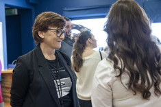 Na pierwszym planie dwie kobiety, jedna ubrana na biało z długi ciemnymi włosami, odwrócona plecami, druga z krótkimi włosami ubrana na czarno. Na zdjęciu: dr arch. K. Kozłowska.