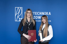 Od lewej: dr inż. arch. Agata Mikrut-Kusy oraz mgr inż. arch. Paulina Więcek pozują do zdjęcia na tle niebieskiej ściany, fot. Arkadiusz Surowiec