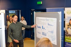 Prezentacja posteru pracy pt. "Analiza awaryjności sieci wodociągowej w wybranym mieście" przez autora mgr. inż. Patryka Pyzaka.