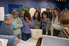 Zgromadzeni goście wystawy słuchają Pani Agaty opowiadającej o swoich haftach