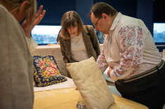 Mężczyzna i kobieta rozmawiają o hafcie zdobiącym żółty obrus