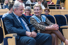 Dwie osoby, mężczyzna i kobieta, siedzące obok siebie podczas rozmowy. W tle uczestnicy wykładu. Od lewej: prof. L. Lichołai, prof. M. Kłos.