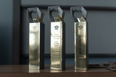 Trzy statuetki od lewej: dla Pani dr inż. Joanny Krasoń, dla Pani mgr inż. arch. Pauliny Wiącek oraz dla Pana mgr. inż. arch. Przemysława Dybasia stoją obok siebie stoją na stole, fot. Arkadiusz Surowiec