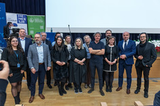 Grupa zgromadzonych kilkunastu osób pozujących do zdjęcia. Większość ubrana na czarno. W tle scena sali wykładowej. Od lewej w pierwszym rzędzie: arch. A. Jóźwiakowska, D. Urbanik, arch. A. Pomykała, prof. arch. A. Sikora, prof. arch. W. Maas, dr. arch. J. Dudek, prez. K. Fijołek, arch. P. Kobierzewski; w drugim rzędzie od lewej: prof. P. Nazarko, prof. L. Lichołai, arch. M. Bober, arch. D. Bober, prof. M. Kłos, dr arch. A. Truszczyński.