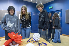 Uczniowie oglądający stojące na stole lampy