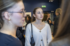 Zdjęcie grupy osób na tle wystawy. Na pierwszym planie dwie młode kobiety. Na zdjęciu na pierwszym planie: studentki kierunku architektura.